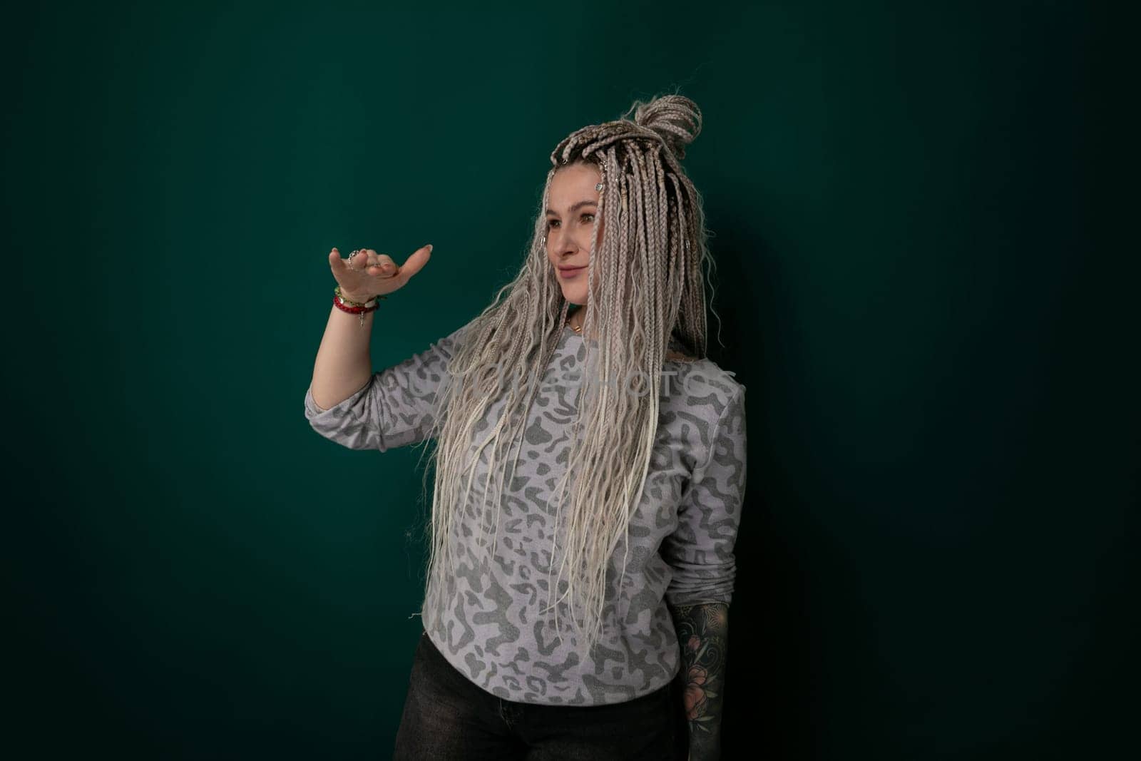 A woman with long hair is standing in front of a solid green wall. She is facing forward, with her hair cascading down her back. The wall provides a simple backdrop to highlight the womans presence.