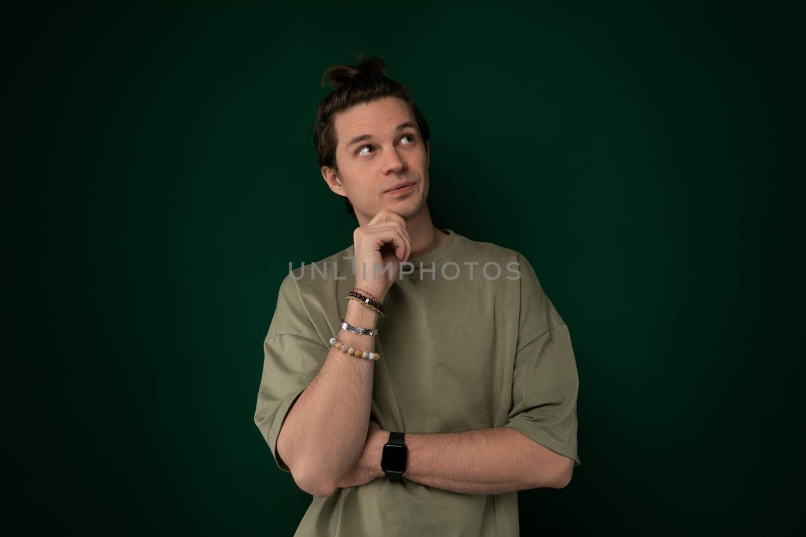 A man is standing with his hand on his chin, deep in thought, contemplating something. He appears focused and introspective, as he ponders a decision or idea.