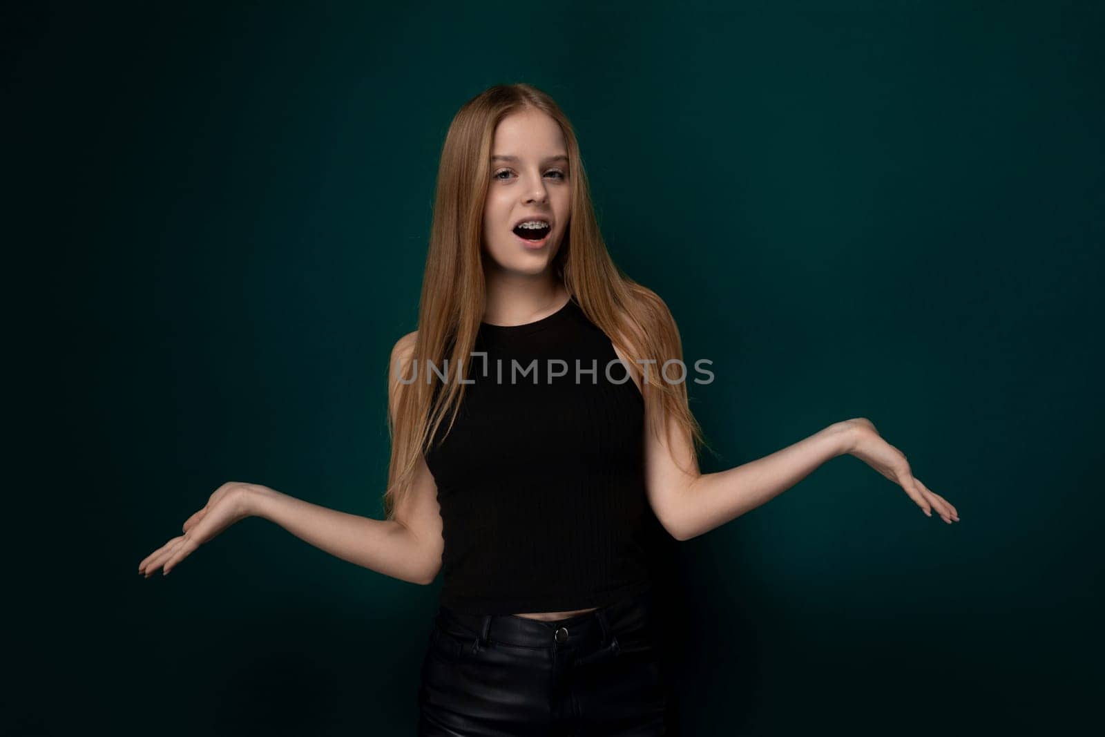A woman with vibrant long red hair is striking a pose for a photograph. She stands confidently as she gazes directly at the camera, showcasing her stunning hair and stylish outfit.