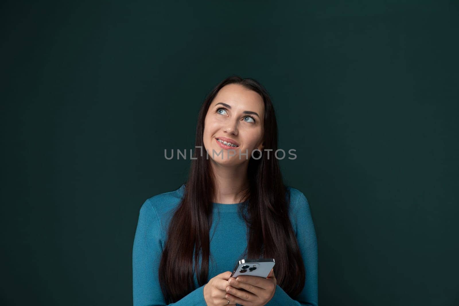 A woman is holding a cell phone in her hands, looking at the screen intently. She appears focused and engaged with the device, possibly texting or browsing the internet.