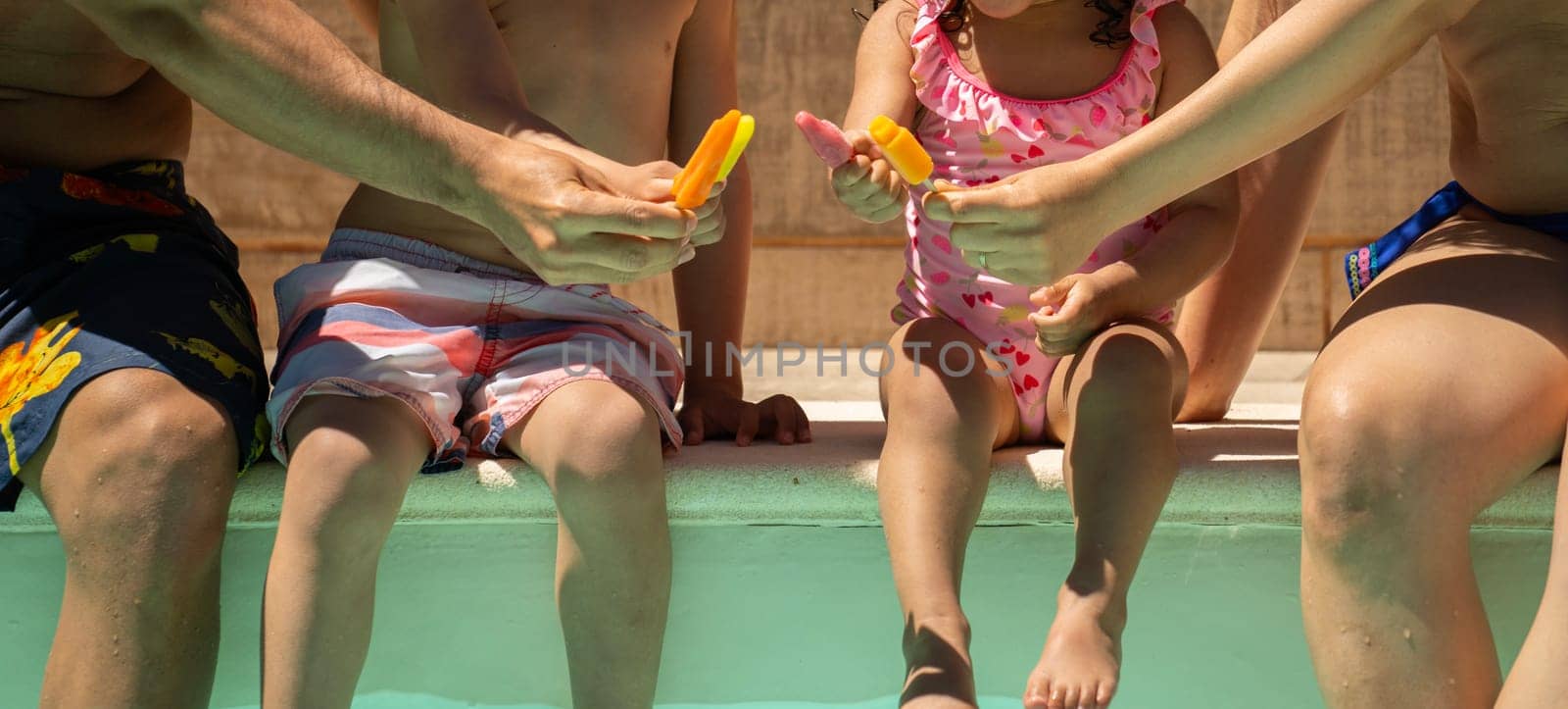 Unrecognizable family of four is sitting in a pool enjoying holidays and showing unity.