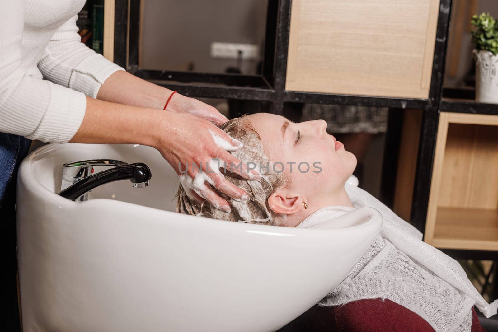 beauty salon master washes client's hair with shampoo for hair care in beauty salon, professional hairdresser,