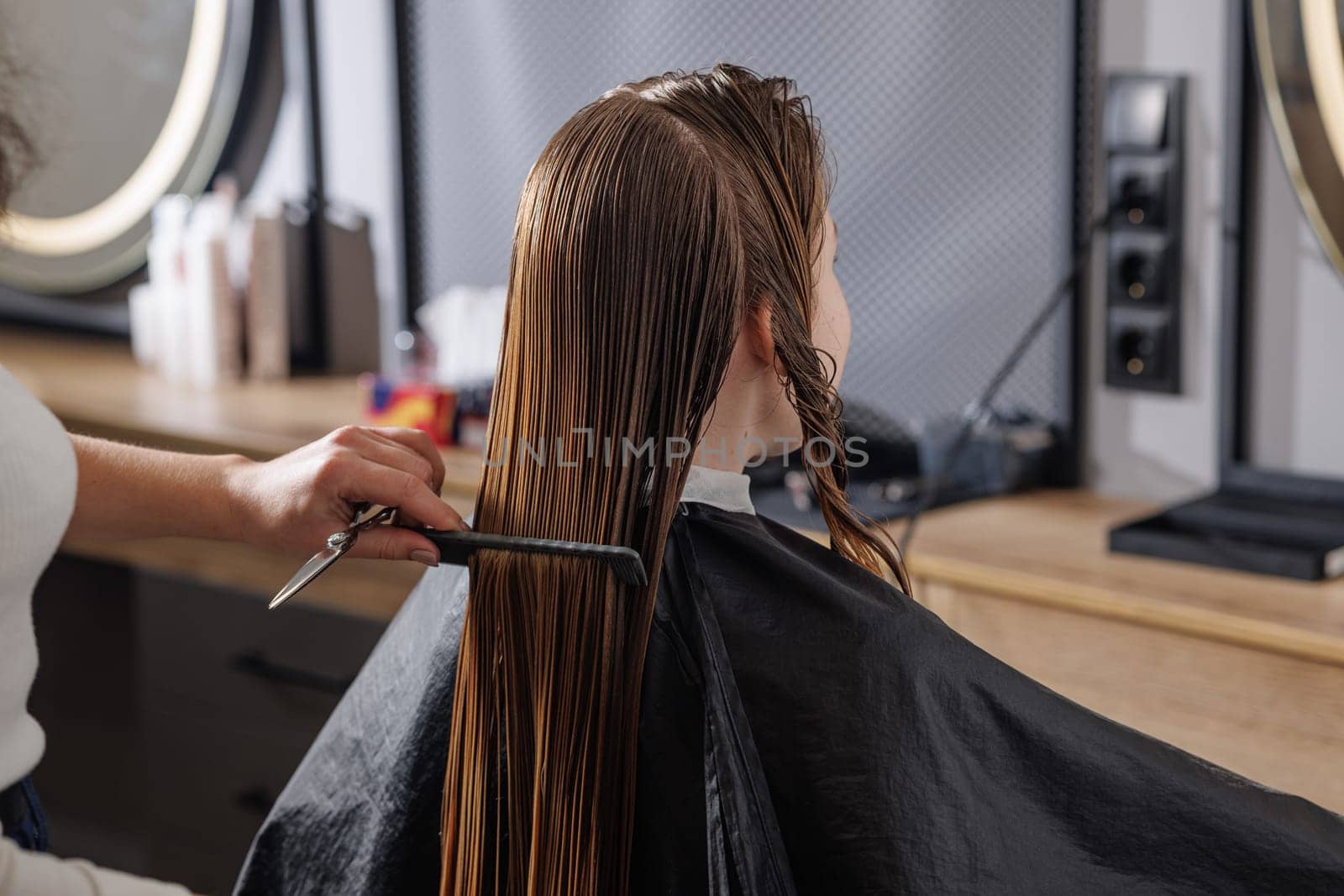 beauty master combing client's wet hair in beauty salon close-up, self-care concept, professional hair care
