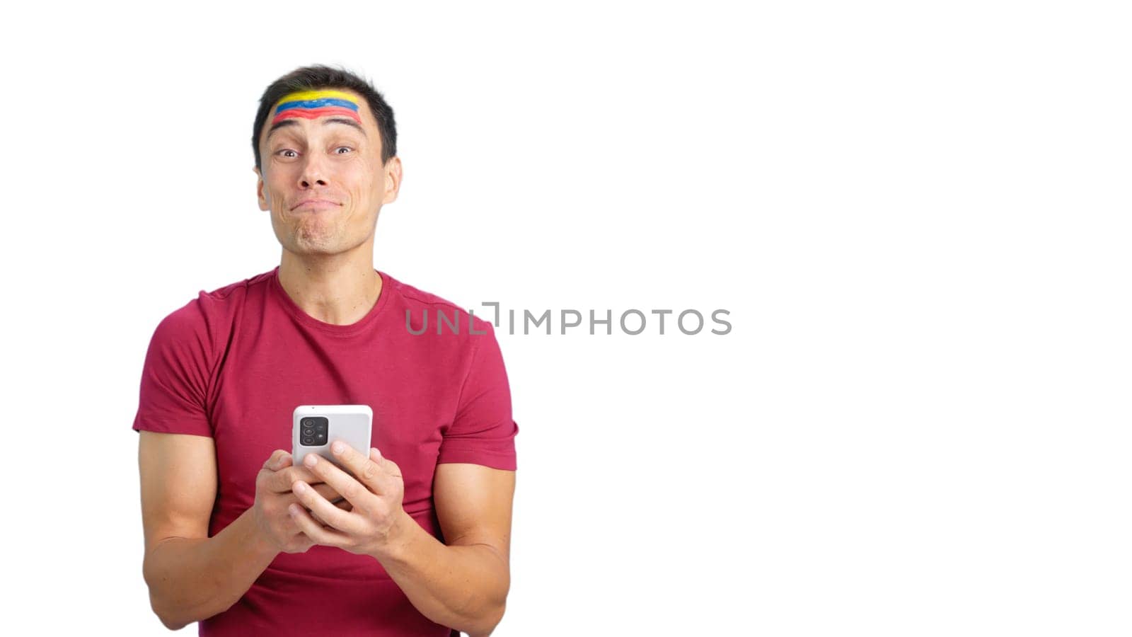 Venezuelan supporter with the flag of Venezuela painted on his face, looking at his mobile phone smiling