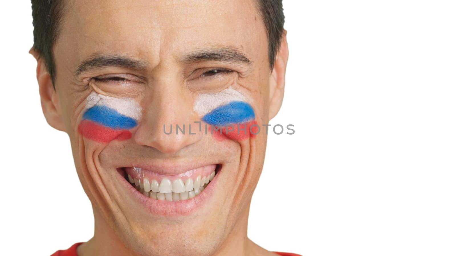 Close up of a man with a russian flag painted on the face smiling at camera