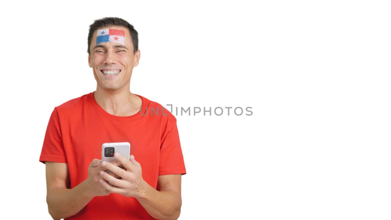 Panamanian supporter with the flag of Panama painted on his face, looking at his mobile phone smiling