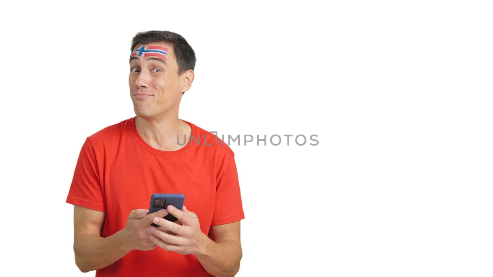 Norwegian supporter with the flag of Norway painted on his face, looking at his mobile phone smiling