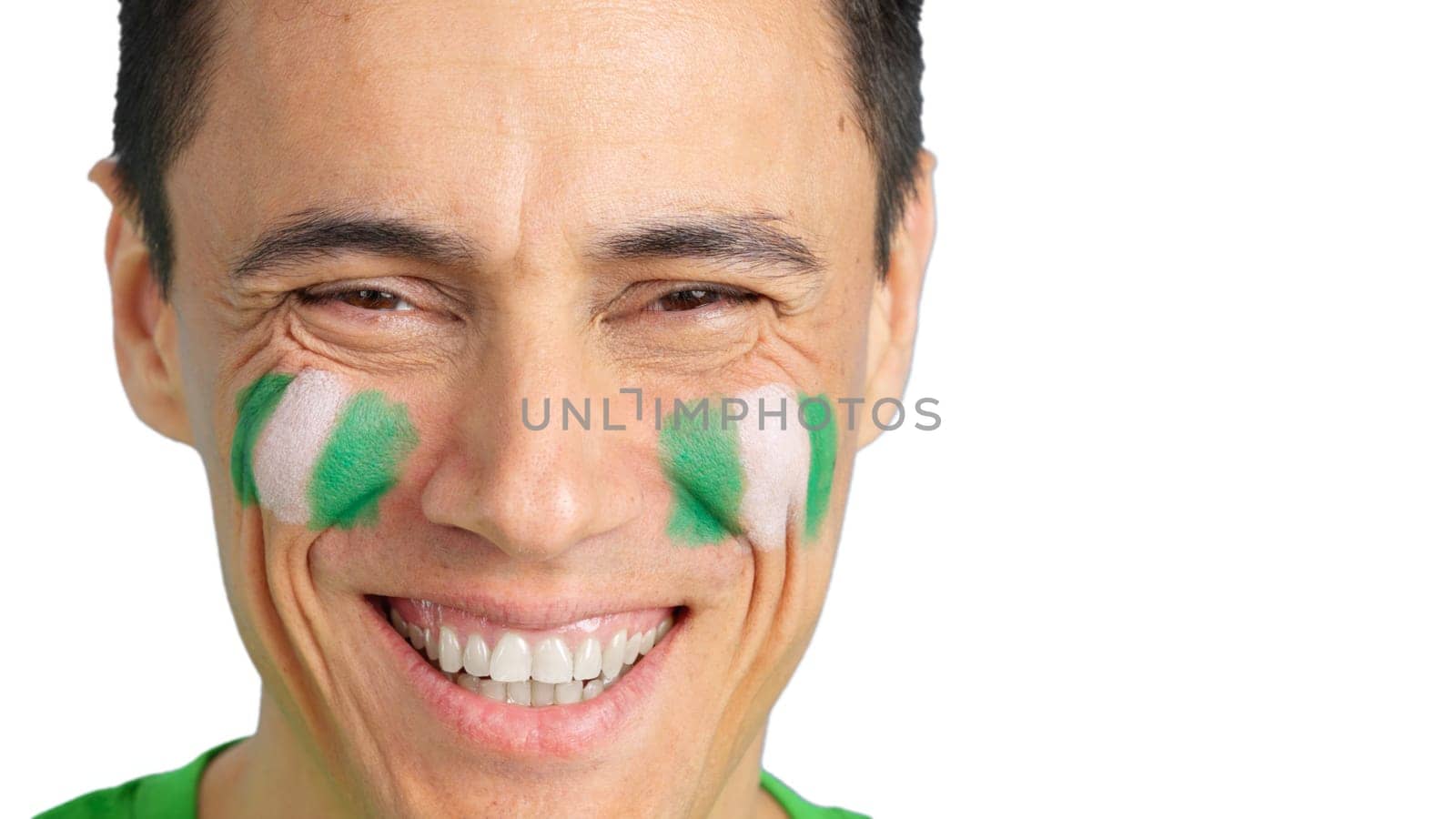 Close up of a man with a nigerian flag painted on the face smiling at camera