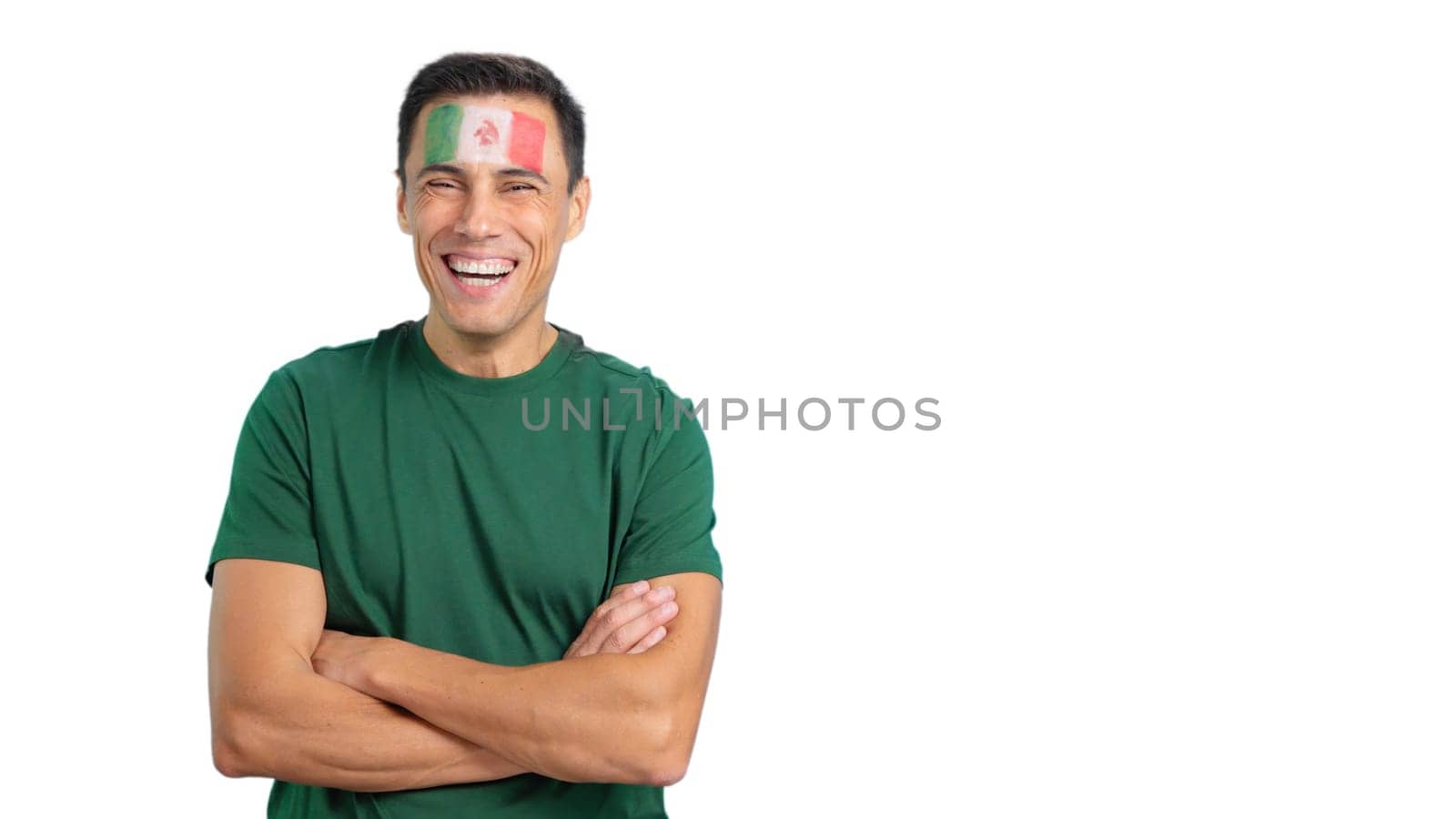 Man standing with mexican flag painted on face smiling with arms crossed