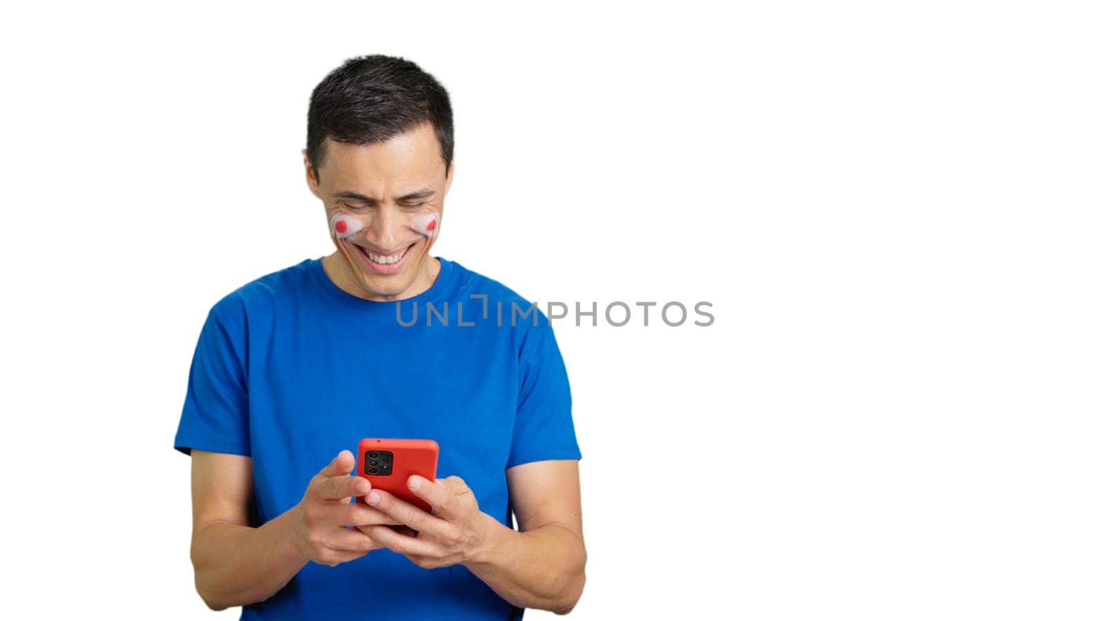 Japan supporter with the flag of Japan painted on his face, looking at his mobile phone smiling