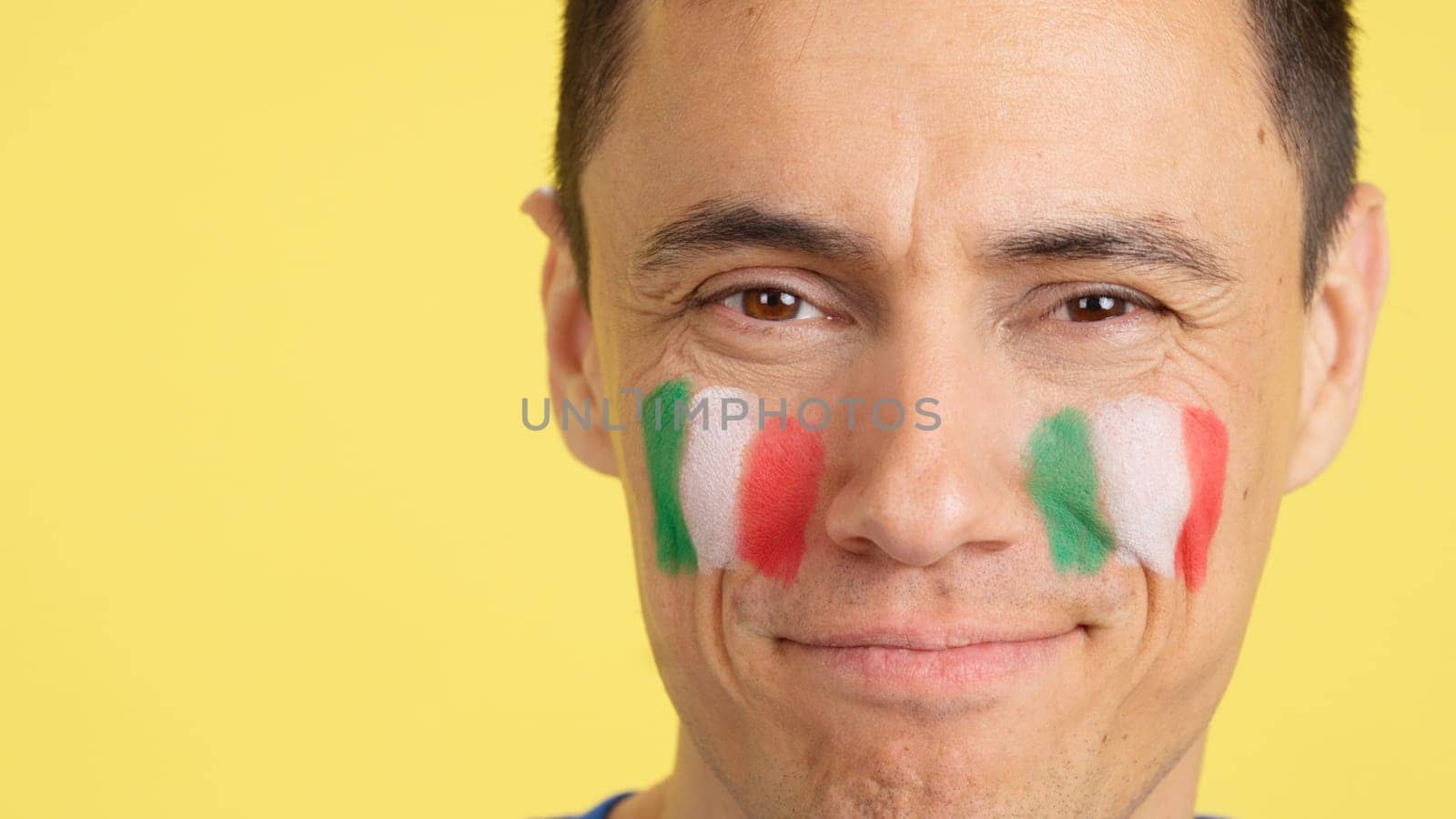 Close up of a man with a italian flag painted on the face supporting italian team