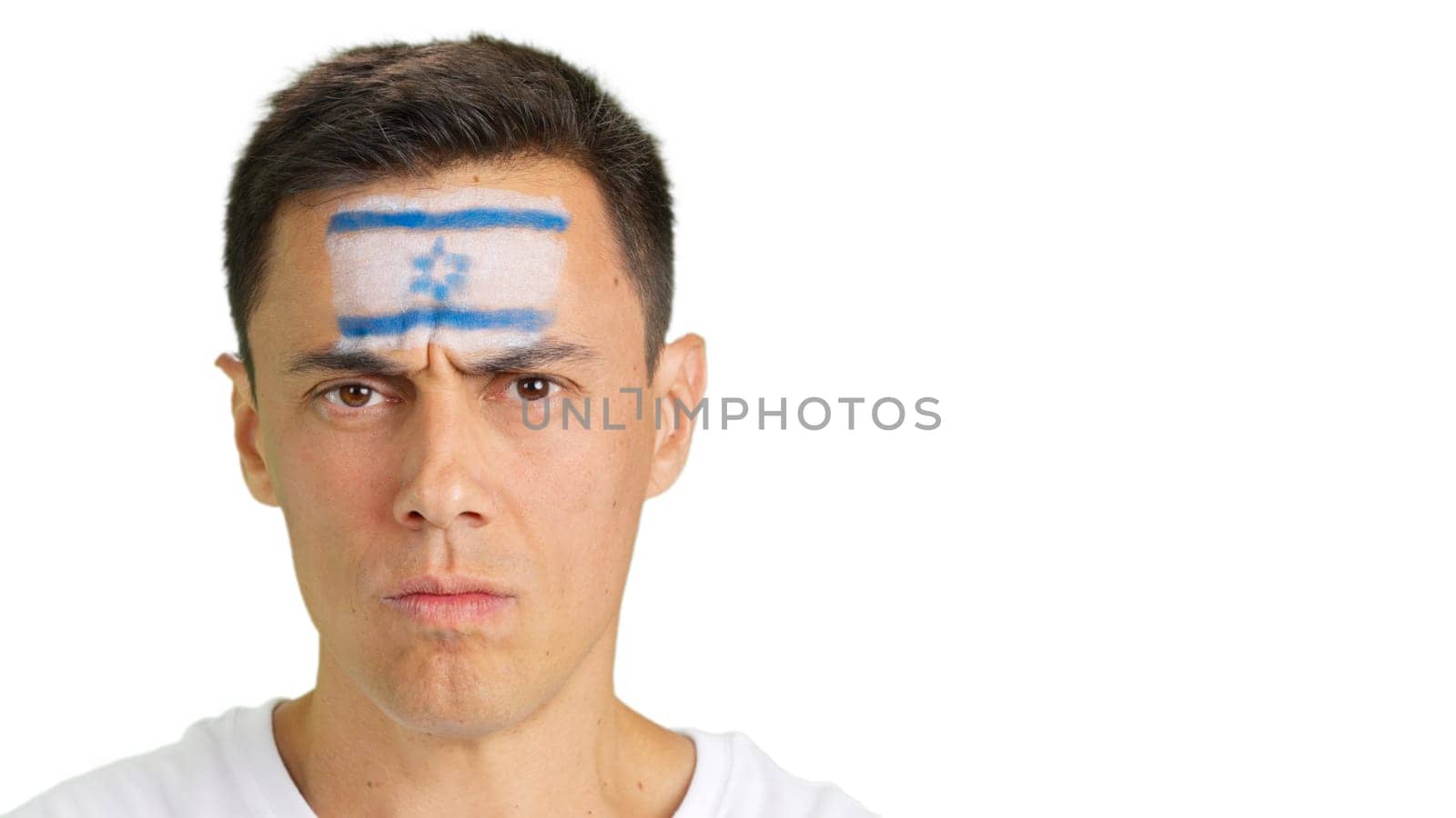 Close up of a serious man with a israeli flag painted on the face looking at camera