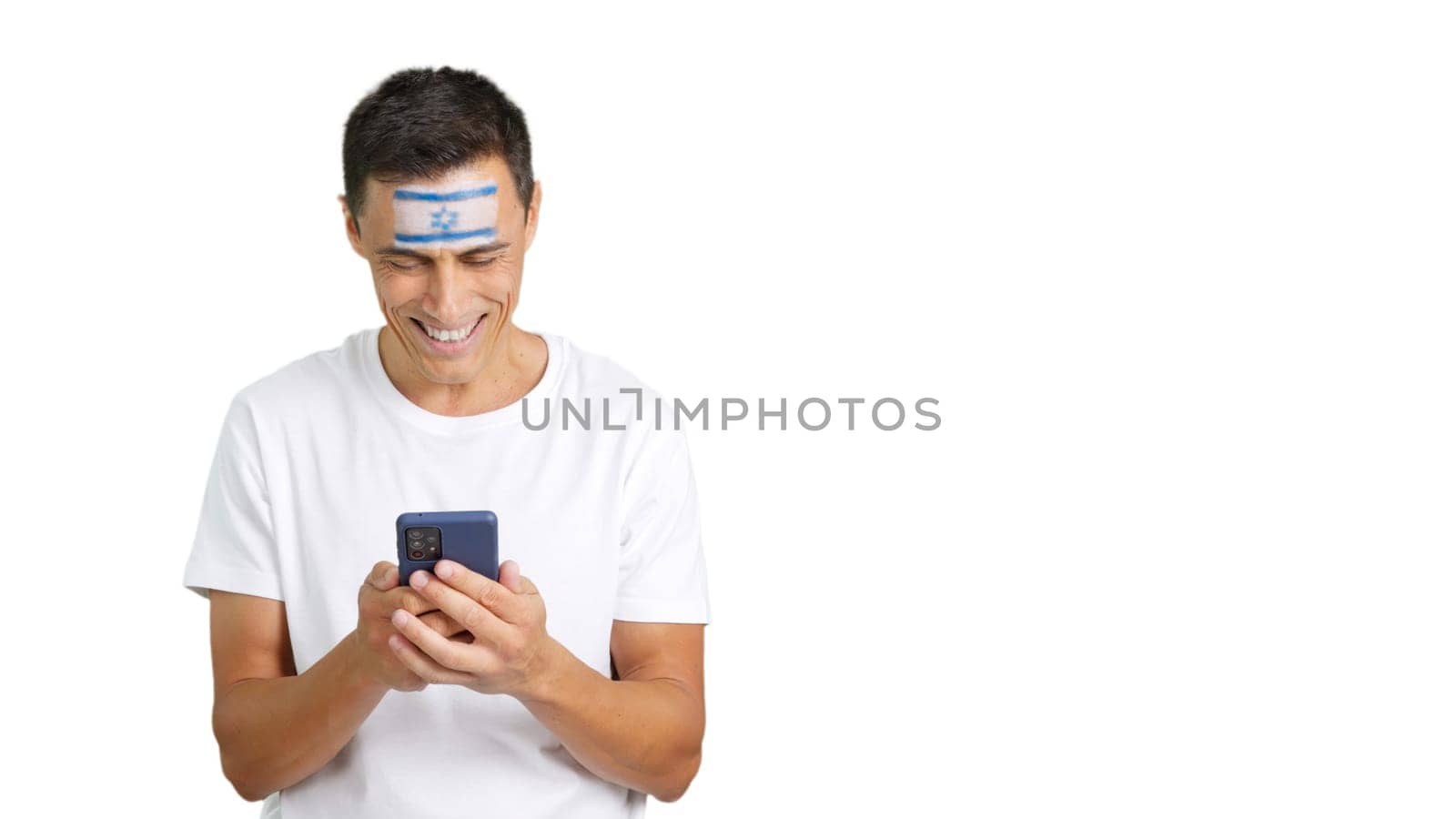 Israeli supporter with the flag of Israel painted on his face, looking at his mobile phone smiling