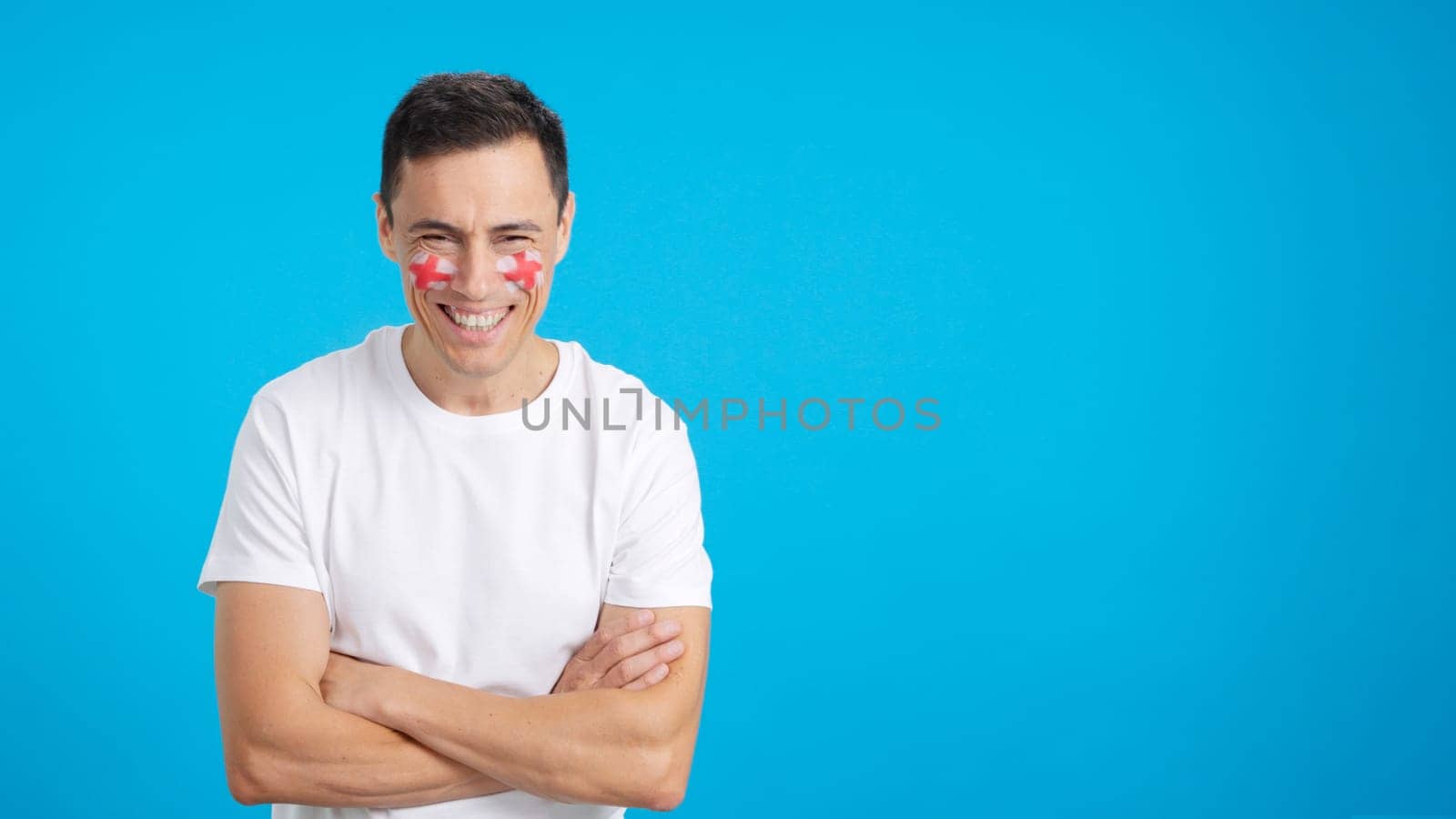 Man standing with english flag painted on face smiling with arms crossed