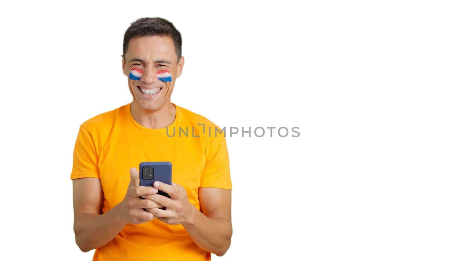 Dutch supporter with the flag of Holland painted on his face, looking at his mobile phone smiling