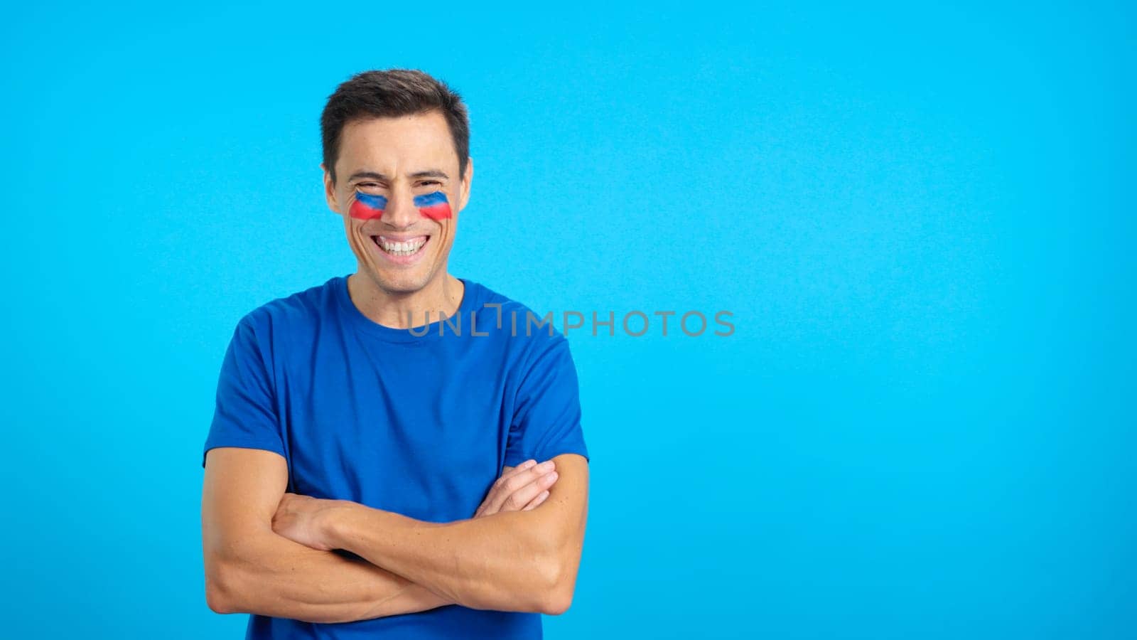 Man standing with haitian flag painted on face smiling with arms crossed