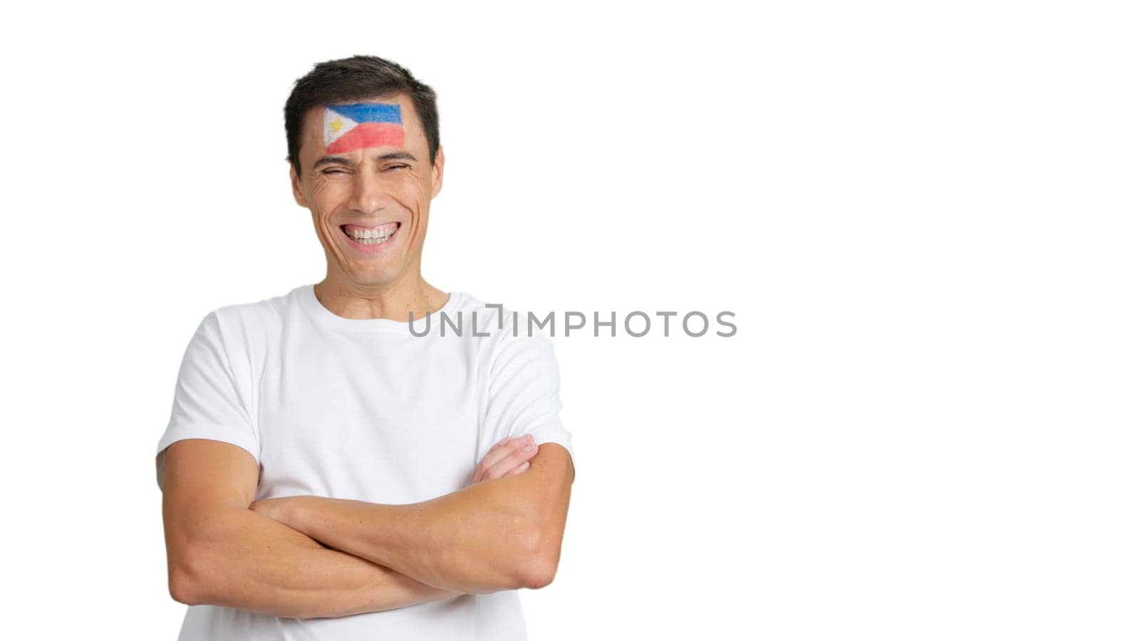 Man standing with philippine flag painted on face smiling with arms crossed