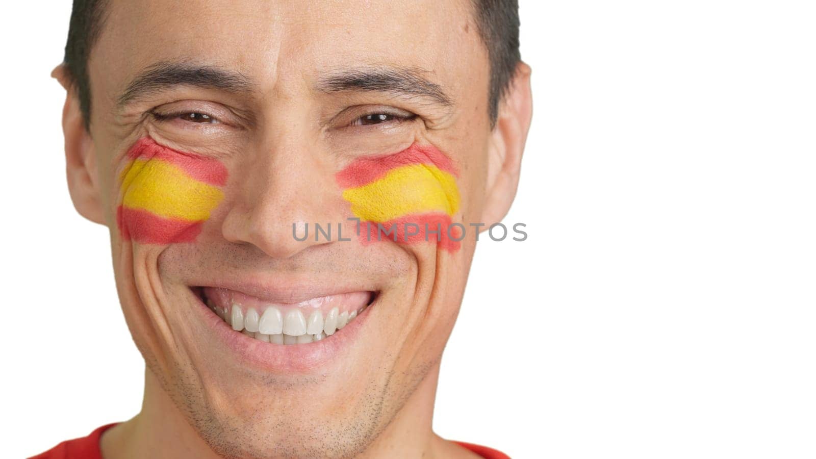 Close-up of a caucasian man with a spanish flag painted on the face smiling at camera