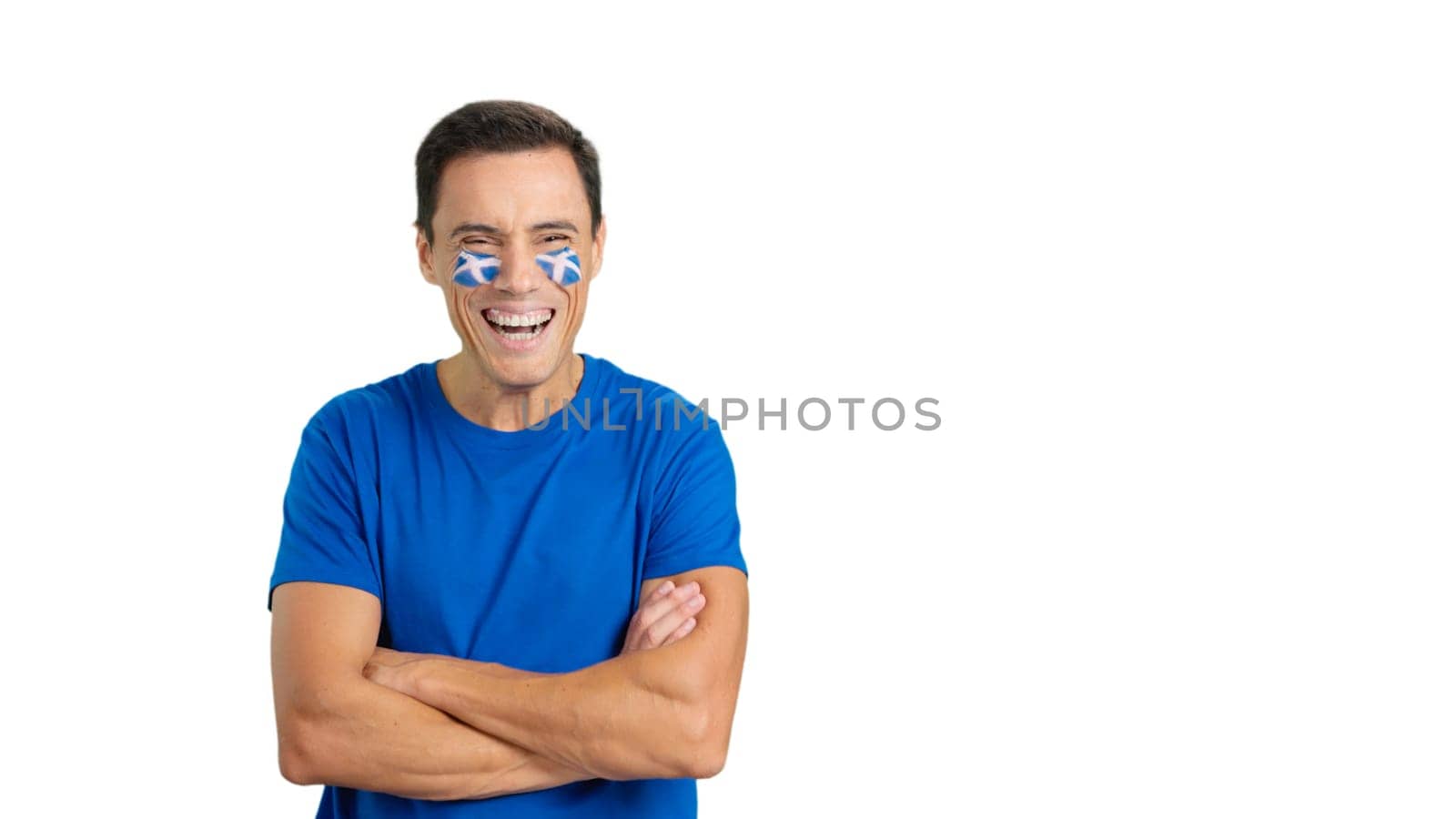 Man standing with scottish flag painted on face smiling with arms crossed