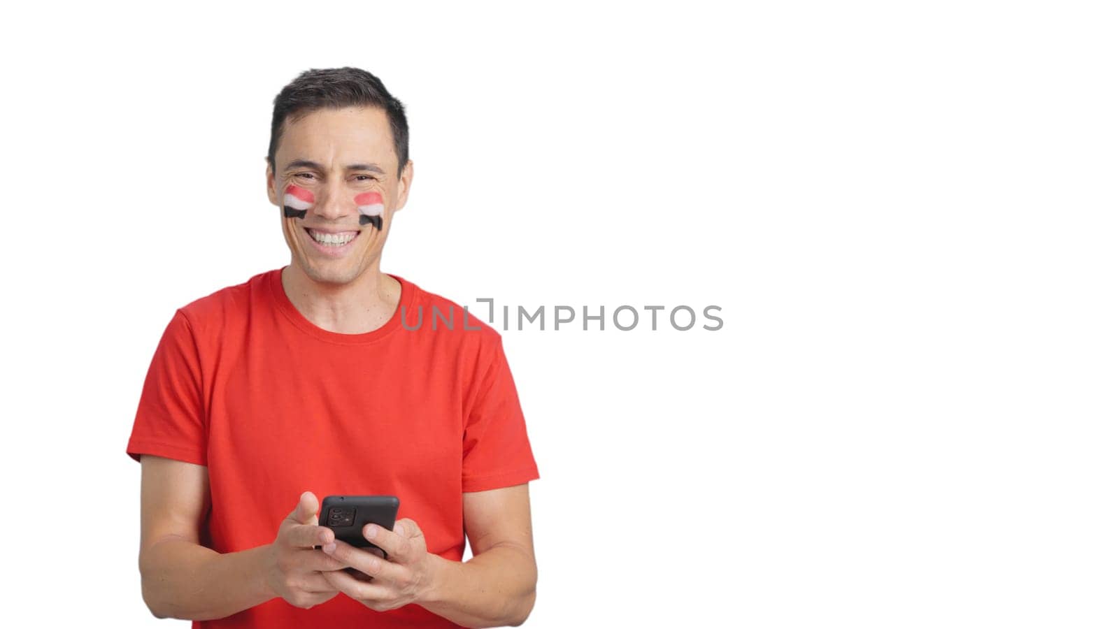 Egypt supporter with the flag of Egypt painted on his face, looking at his mobile phone smiling