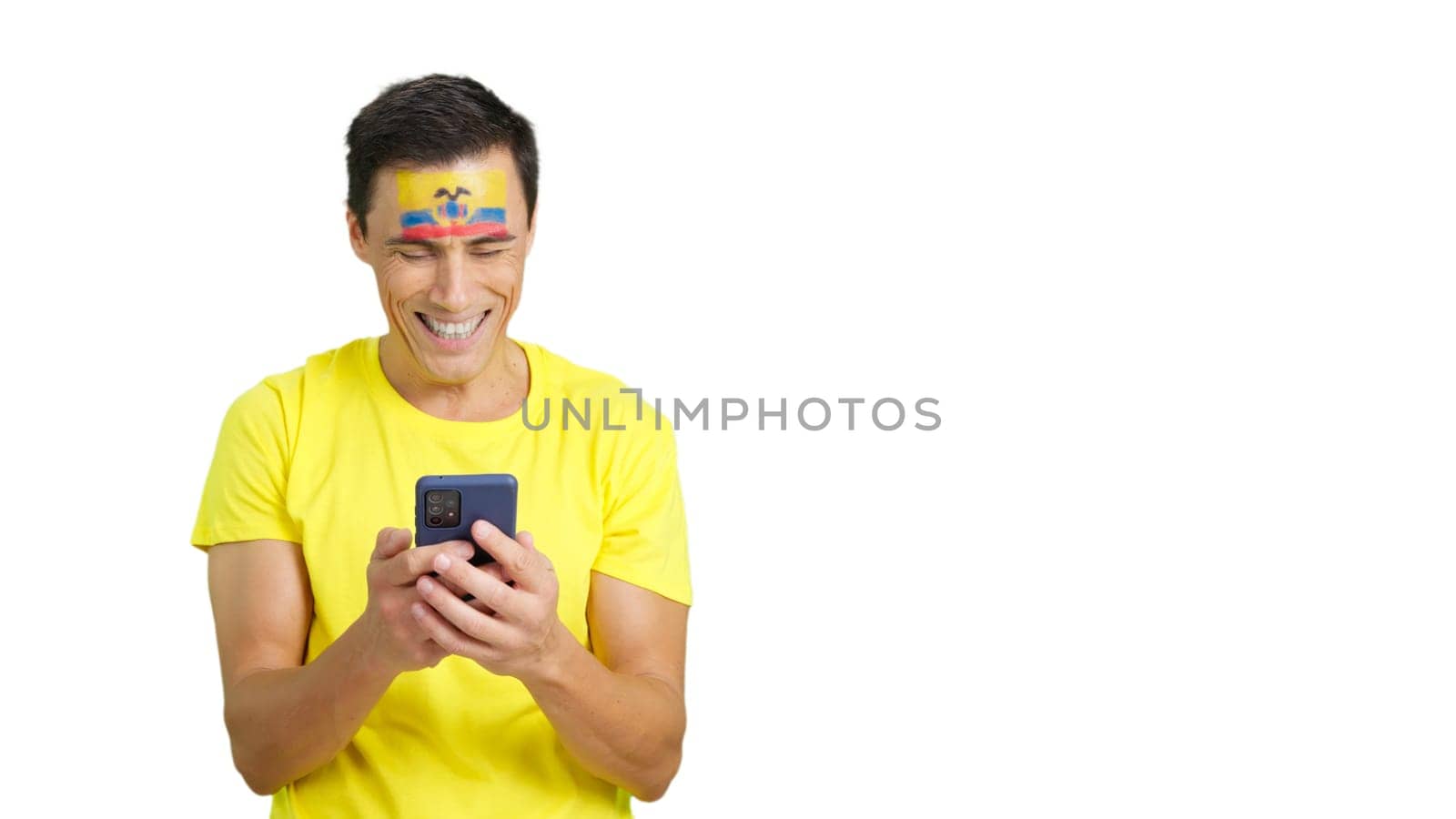 Ecuadorian supporter with the flag of Ecuador painted on his face, looking at his mobile phone smiling