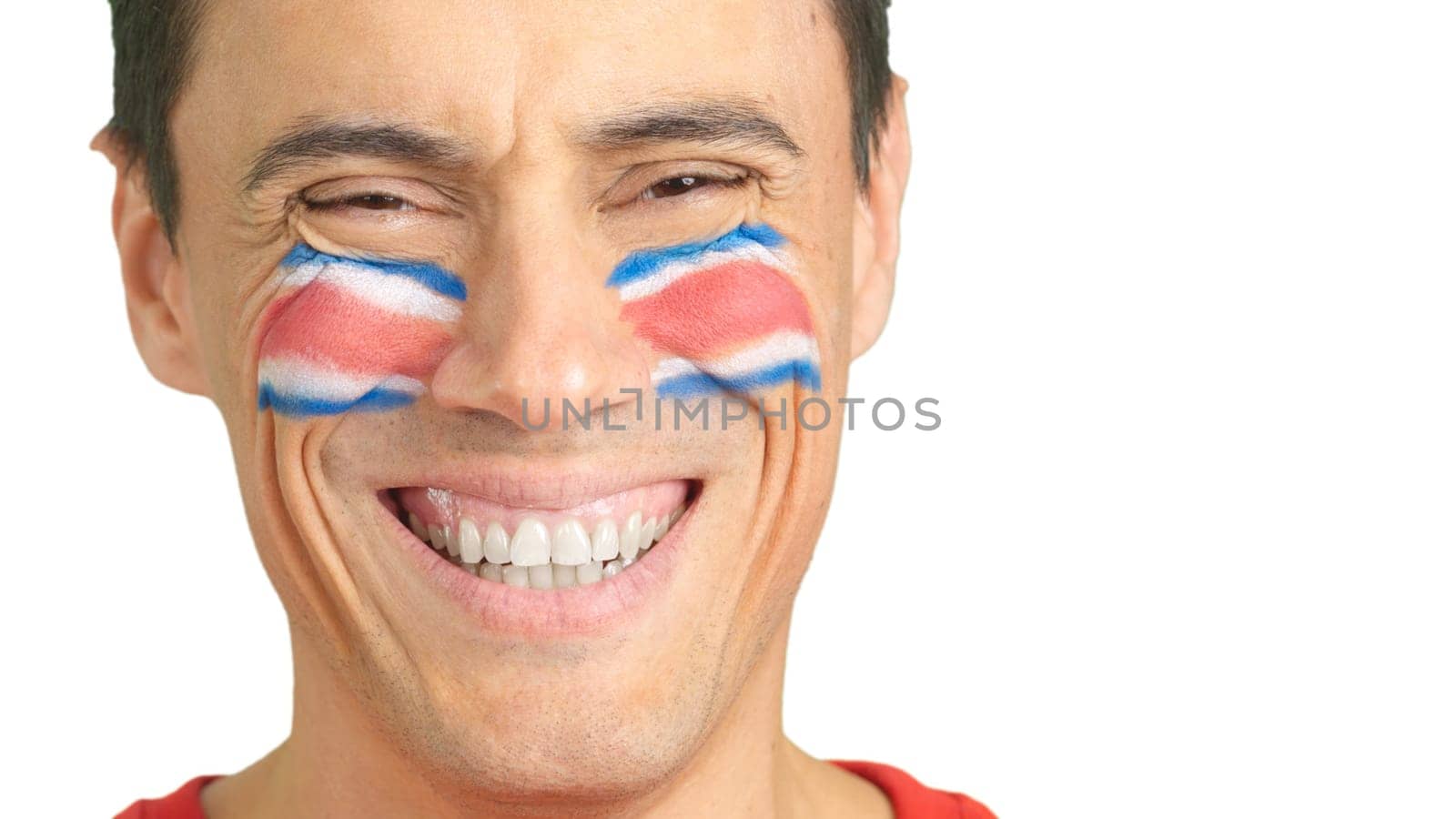 Close up of a man with a costa rican flag painted on the face smiling at camera