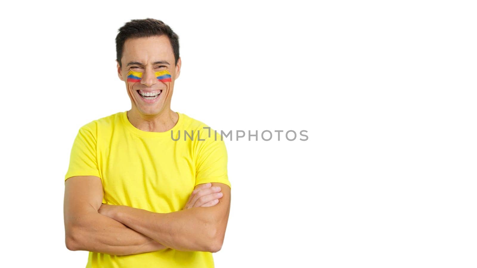 Man standing with colombian flag painted on face smiling with arms crossed
