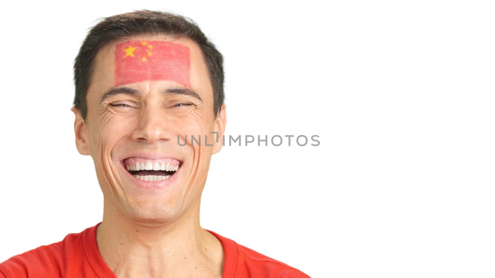 Close up of a caucasian man with a chinese flag painted on the face smiling at camera
