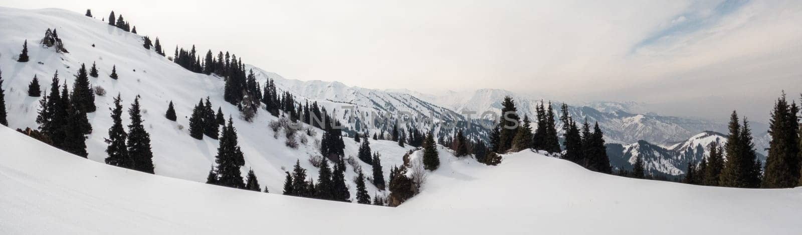 Snow-covered slopes in the winter mountains of central Asia. Banner landscape in the highlands of central asia.