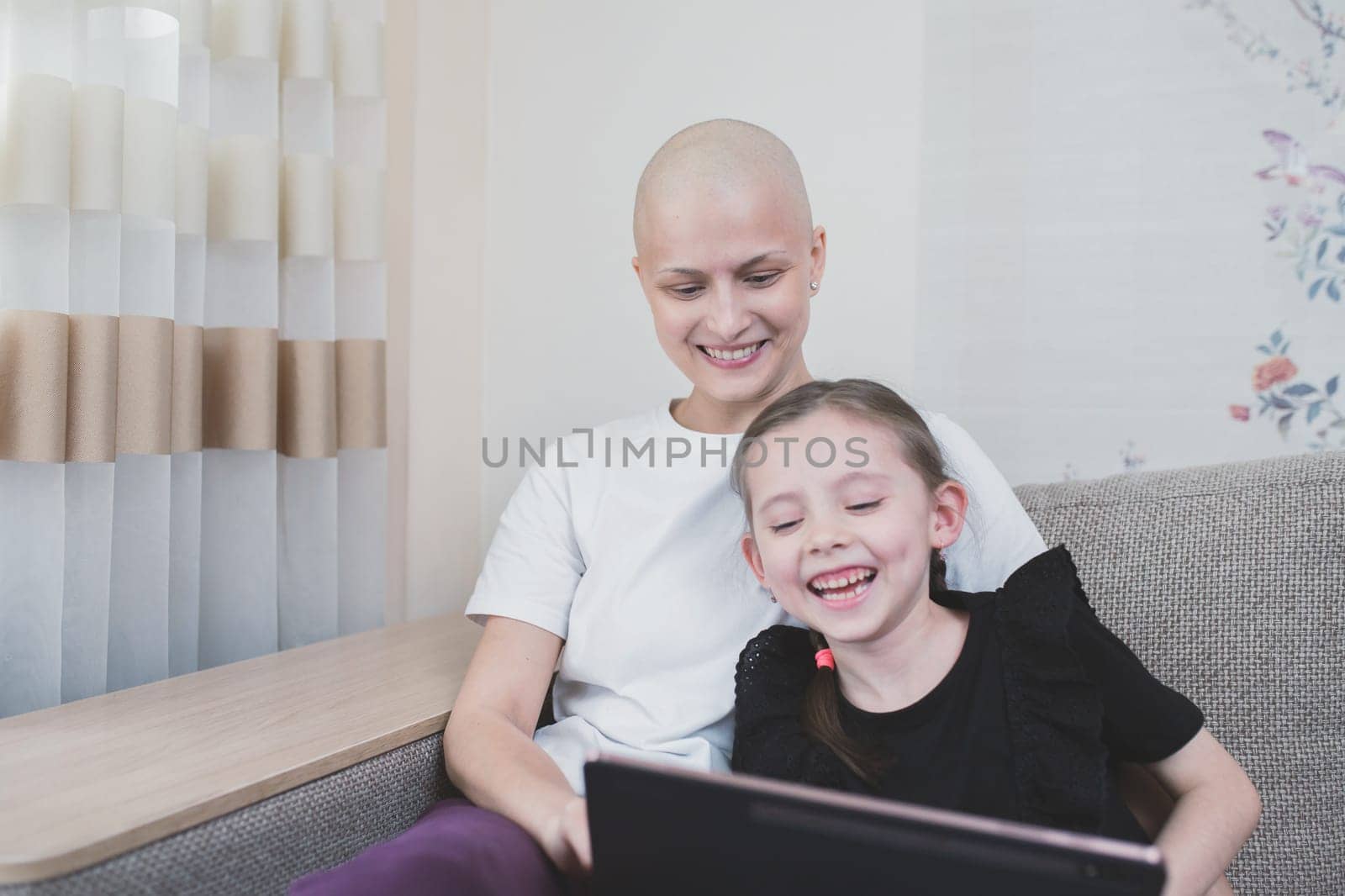 Child girl joyful spend time with her mother with a diagnosis of oncology after chemotherapy. Family support concept.