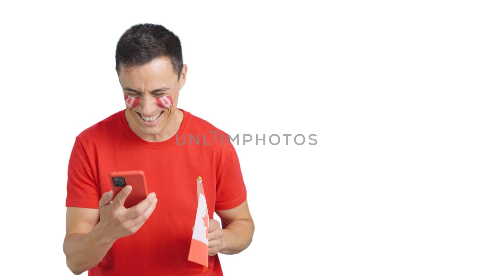 Canadian supporter with the flag of Canada painted on his face, looking at his mobile phone smiling