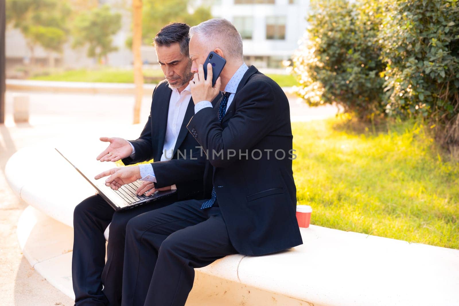 Two businessmen with laptop in hand looking at the results of the project. by mariaphoto3