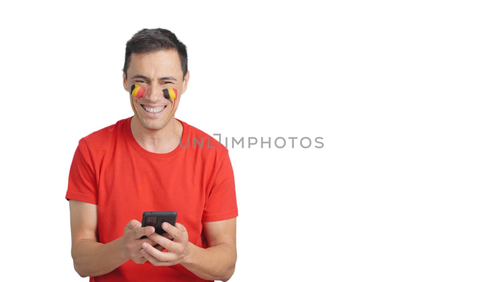 Belgian supporter with the flag of Belgium painted on his face, looking at his mobile phone smiling