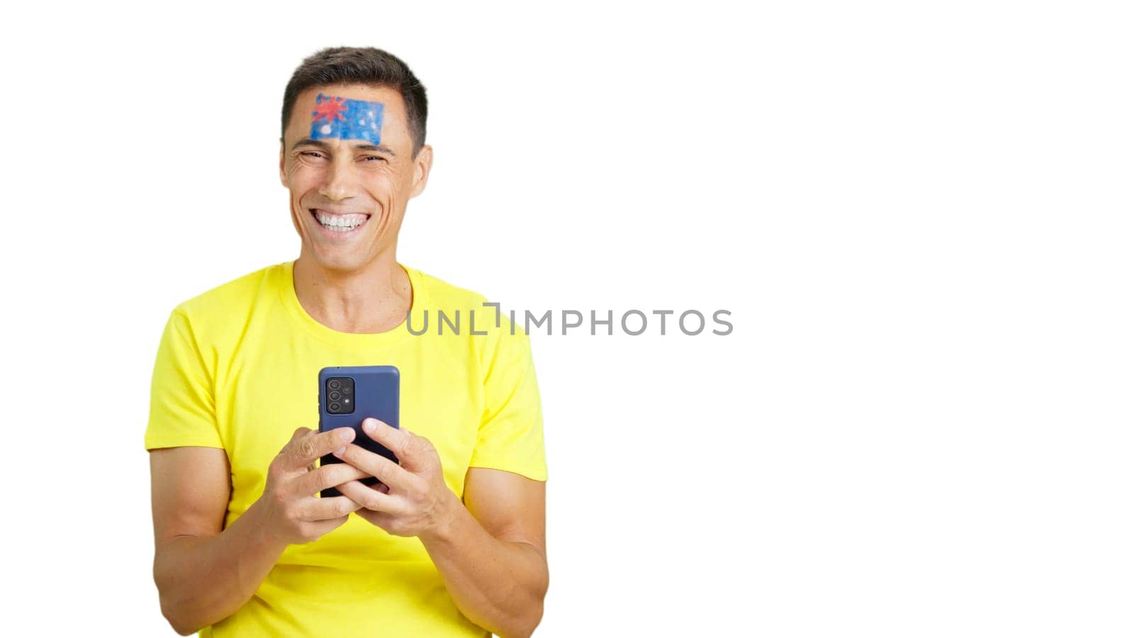 Australian supporter with the flag of Australia painted on his face, looking at his mobile phone smiling