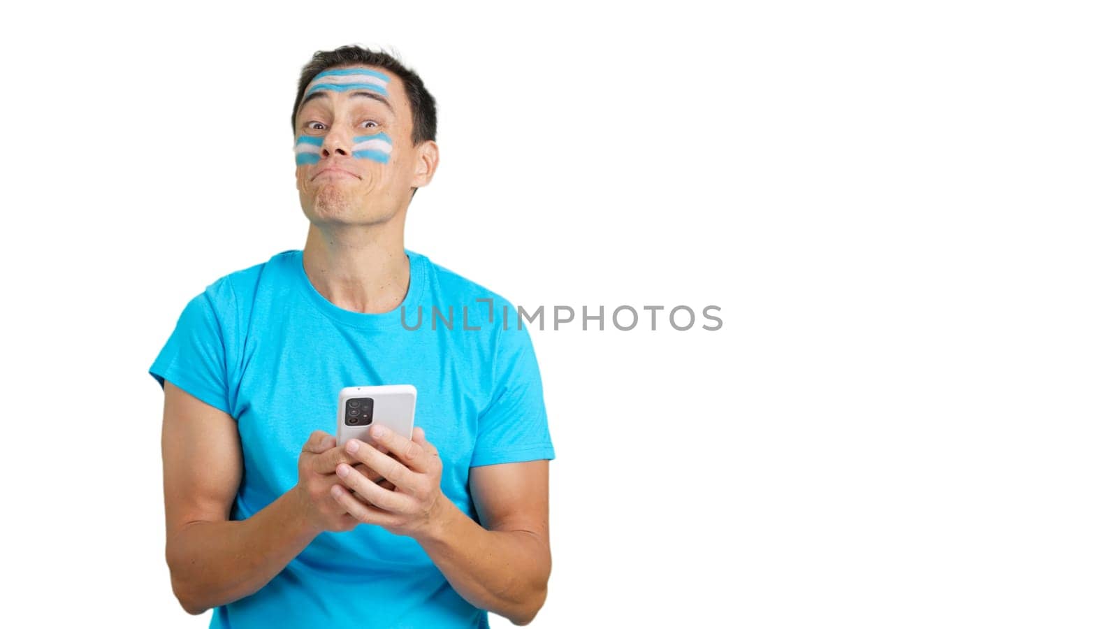 Argentina supporter with the flag of Argentina painted on his face, looking at his mobile phone smiling
