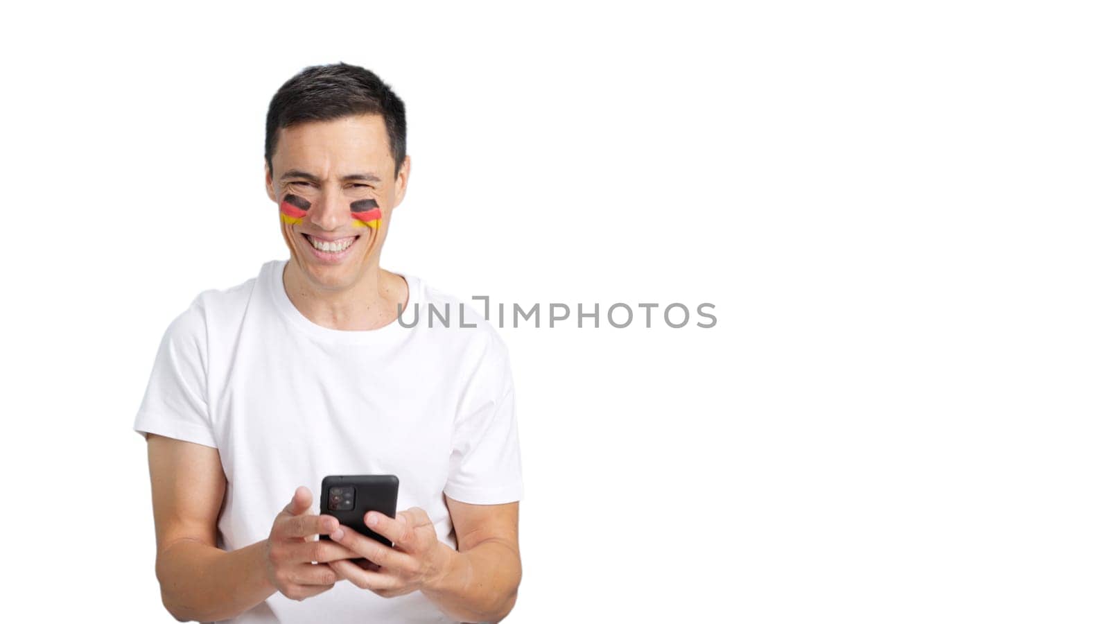German man with the flag of Germany painted on his face, looking at his mobile phone smiling