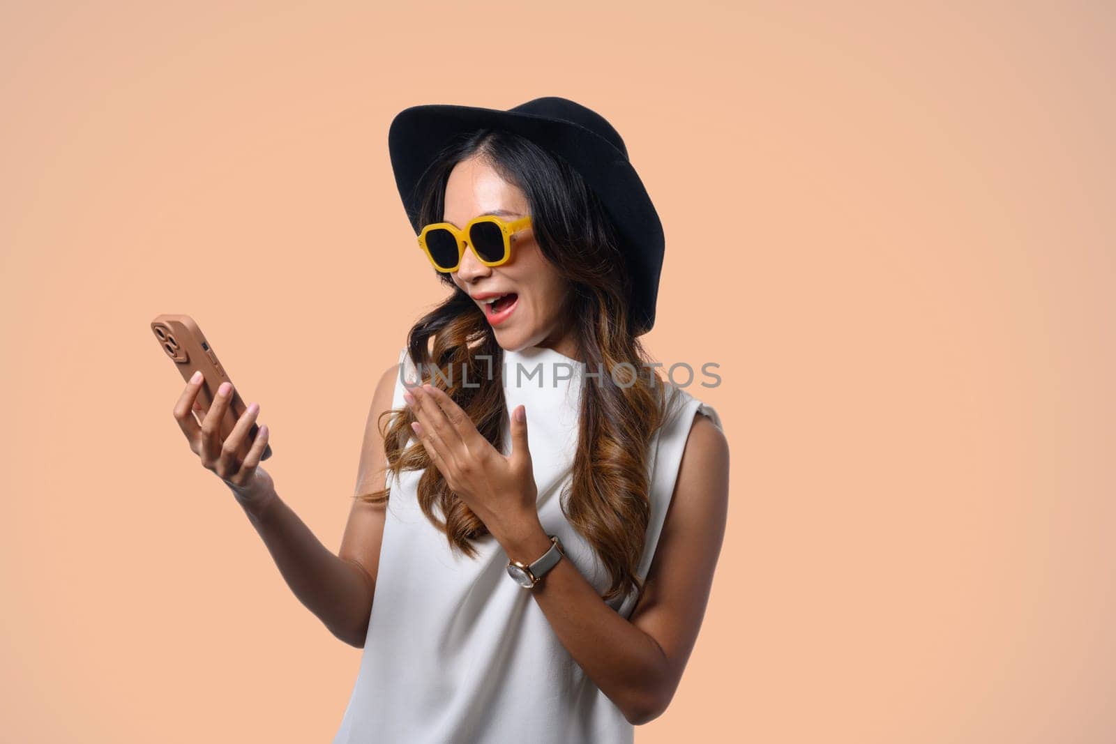 Shocked young woman in summer clothes with shocked reaction looking at mobile phone.