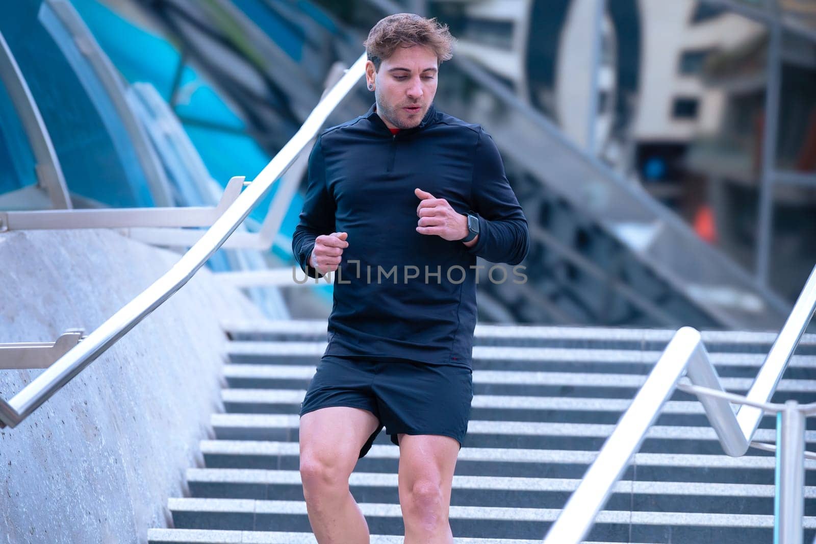 Man running down stairs,with bottle of water in hand doing his daily cardio and warm up exercise. Physical activity concept