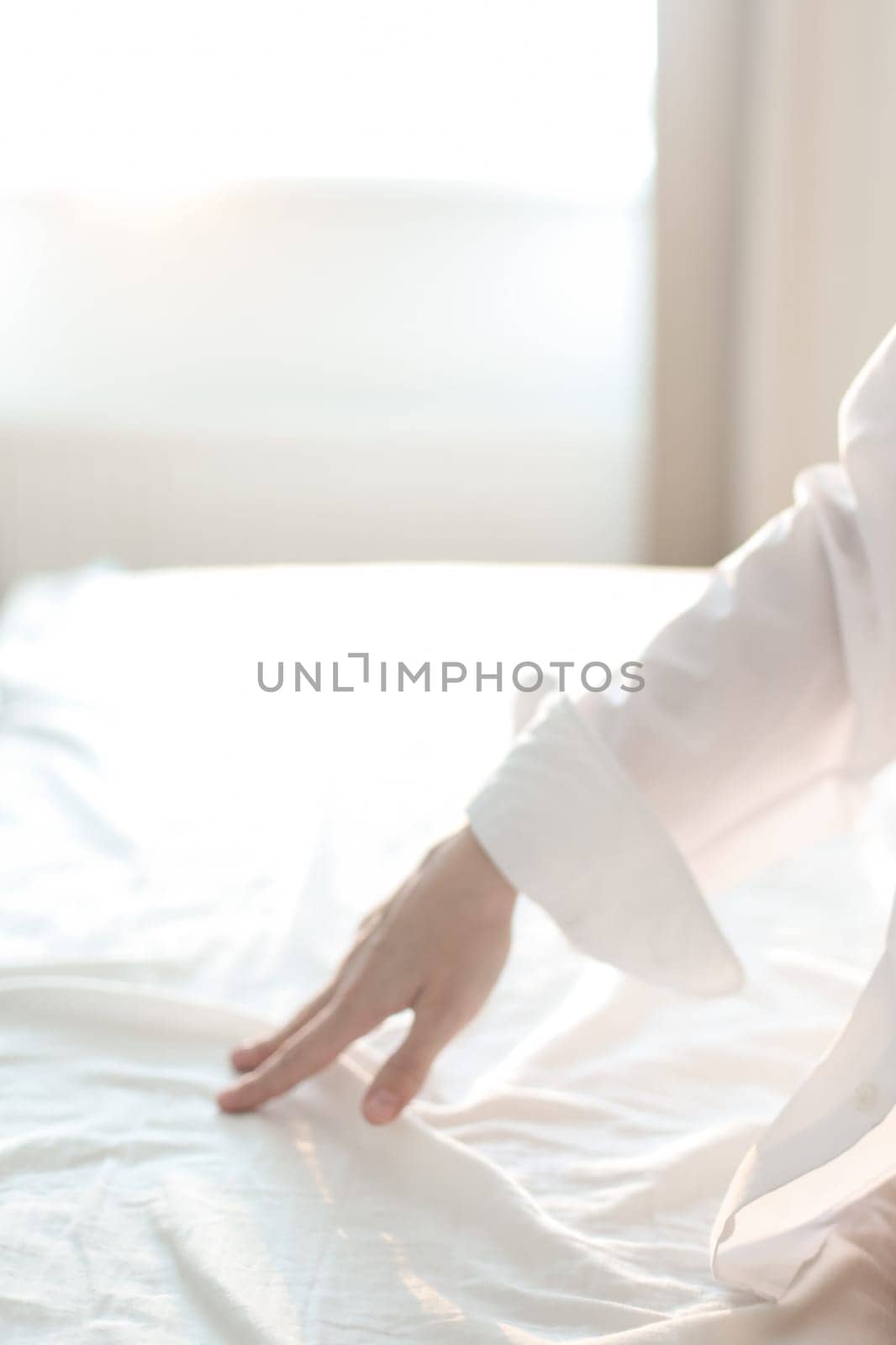 Woman Hand touching bed sheets, closeup. Young woman intimacy on bed. Soft, gentle, tender cozy morning concept