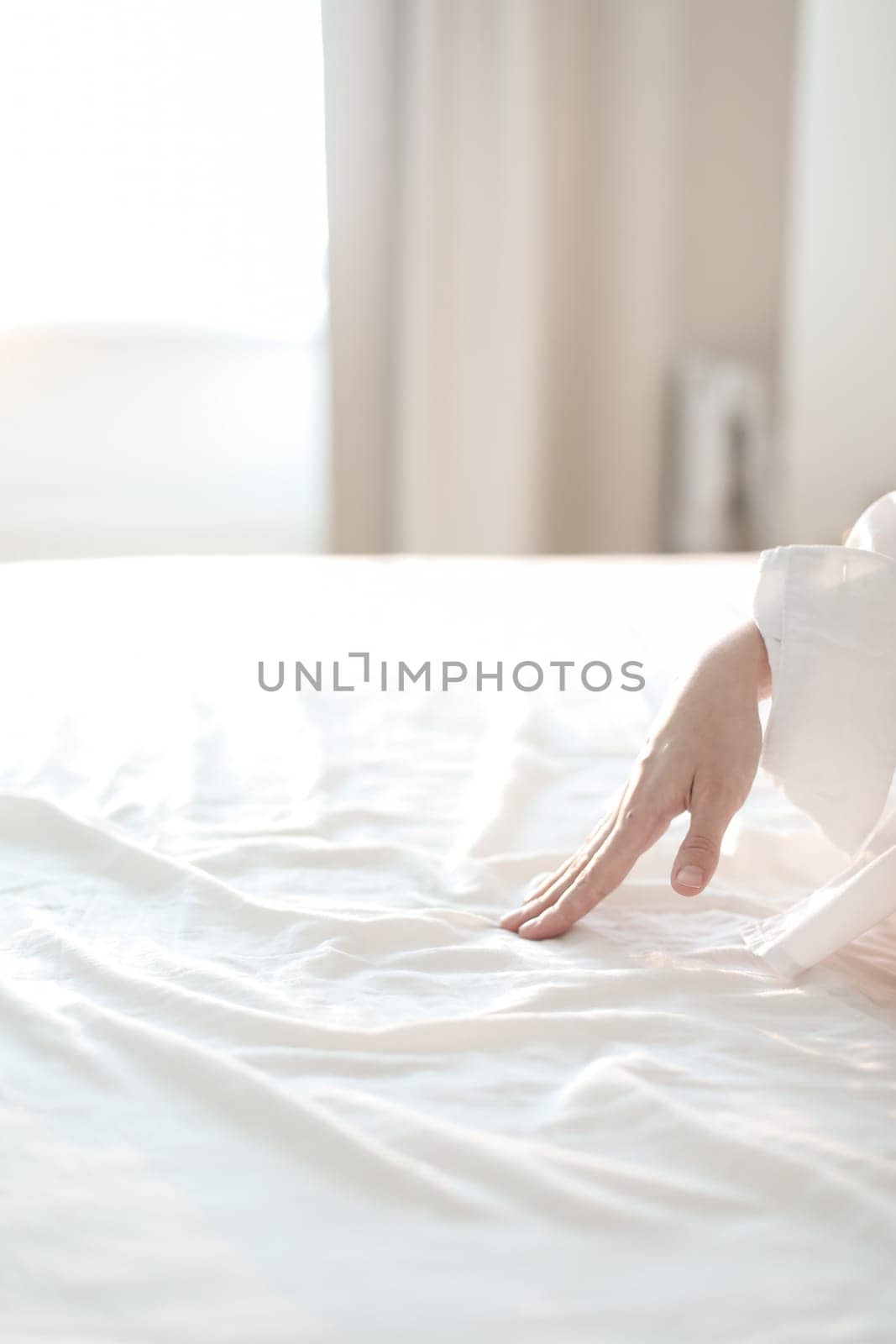 Woman Hand touching bed sheets, closeup. Young woman intimacy on bed. Soft, gentle, tender cozy morning concept