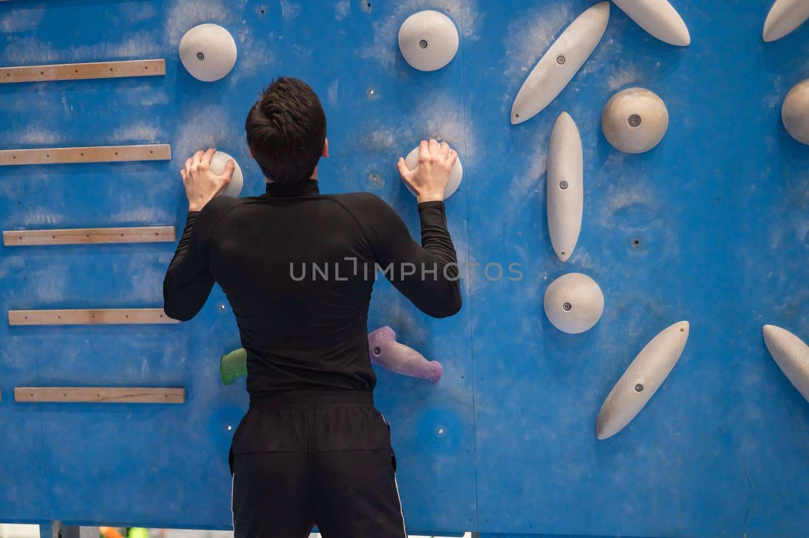 Caucasian man training on a climbing wall. by mrwed54