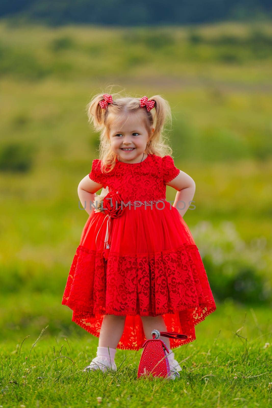 little girl in a red dress walks on the lawn