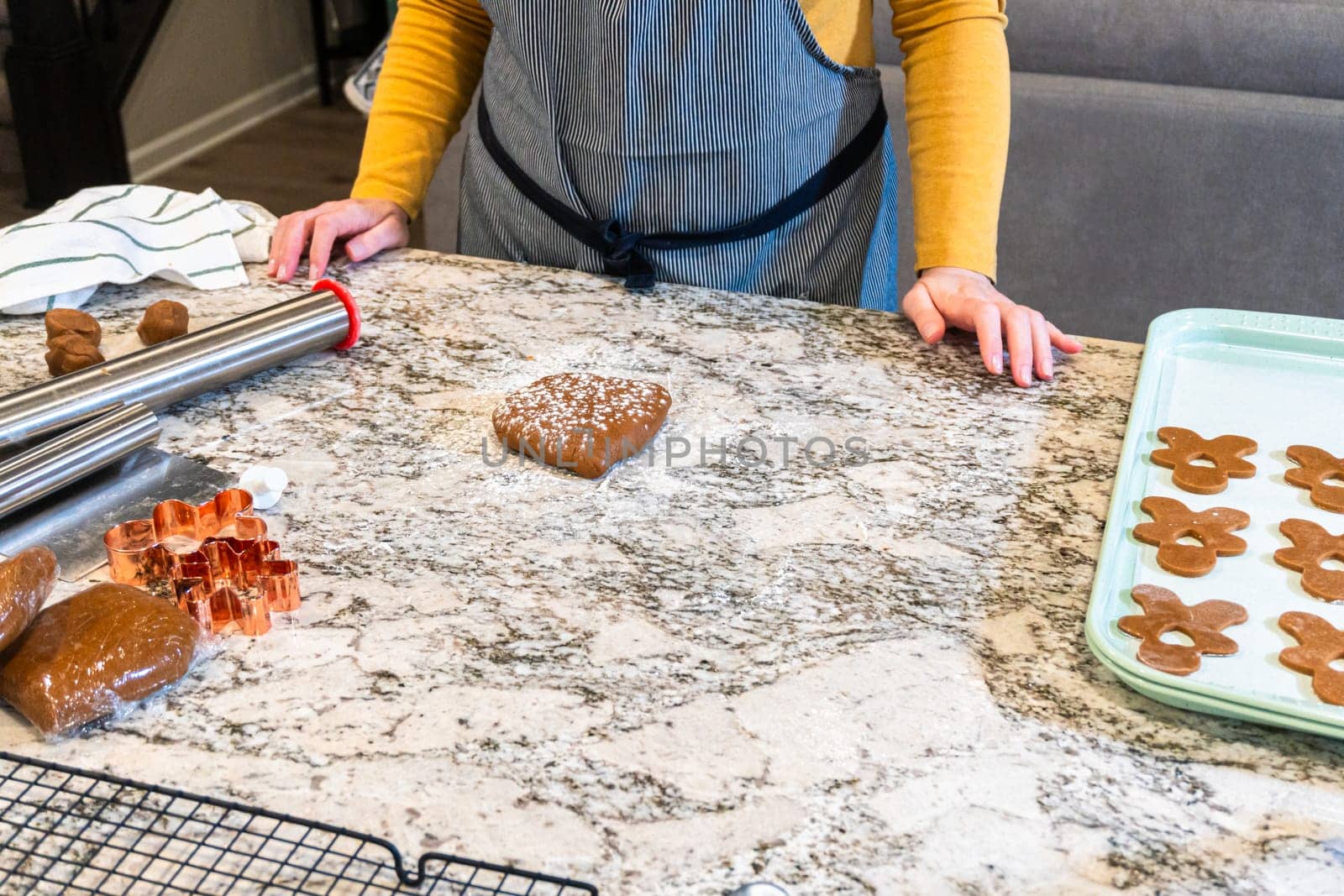 In a contemporary white kitchen, gingerbread cookie dough is skillfully rolled out, setting the stage for a delightful holiday treat.