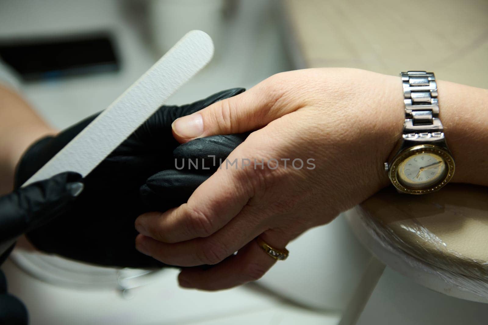 Close-up of a professional manicurist performing nail care in a beauty salon. Hands receiving a manicure treatment.