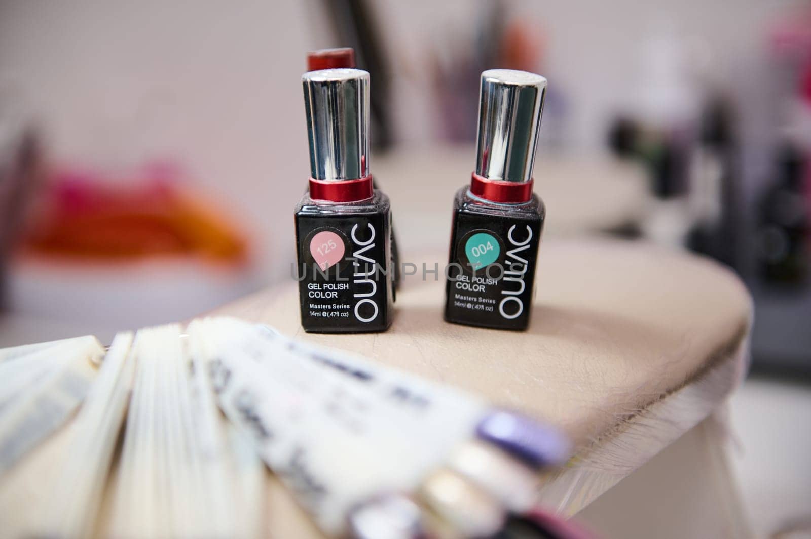 Close-up of gel nail polish bottles on a table in a beauty salon, showcasing various colors for clients.