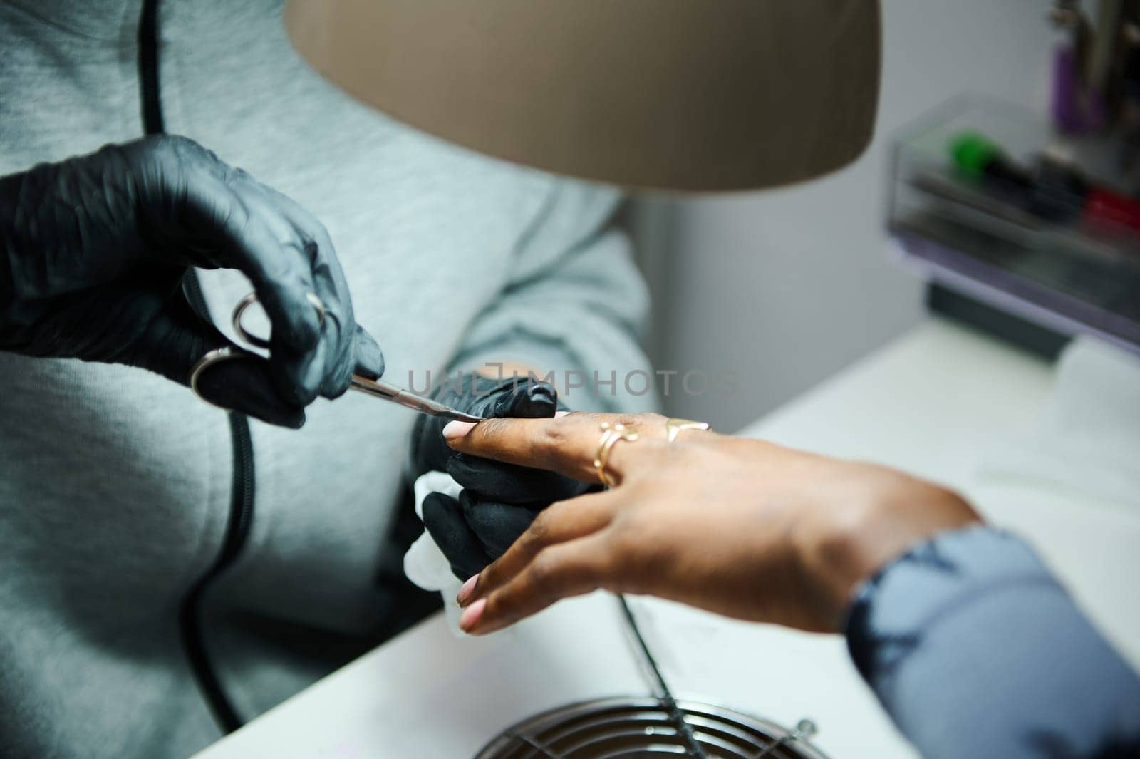 Professional manicure session at a beauty salon. A client receives expert nail care and grooming from a skilled technician wearing gloves.