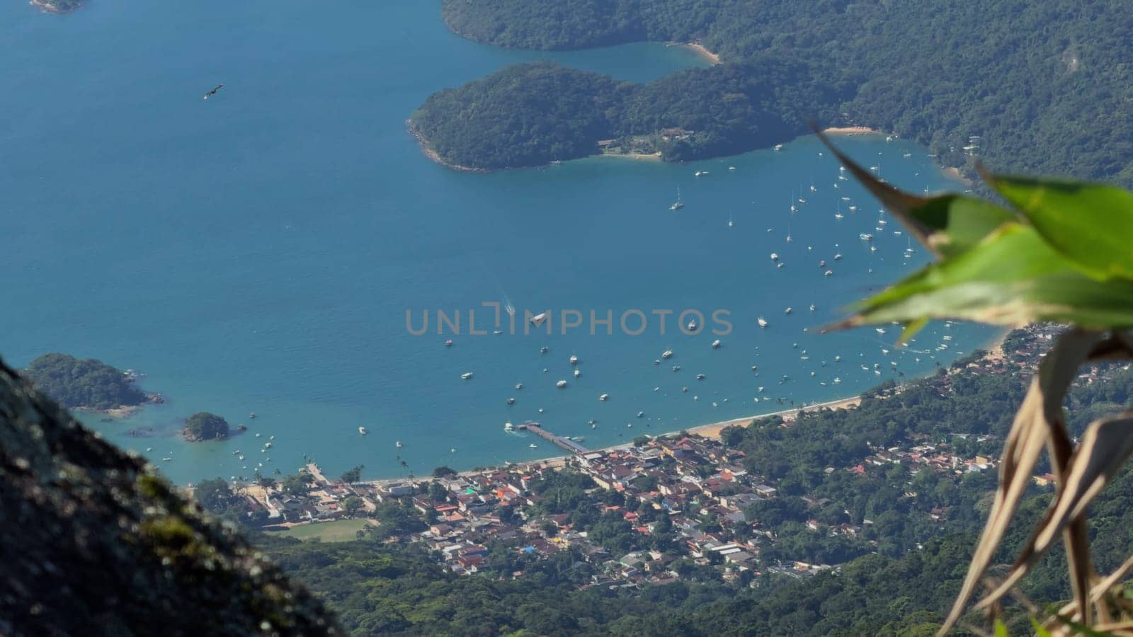 A stunning aerial video of Ilha Grande, Brazil, featuring dense forests, rocky shores, coastal boats, and the town of Abrao.