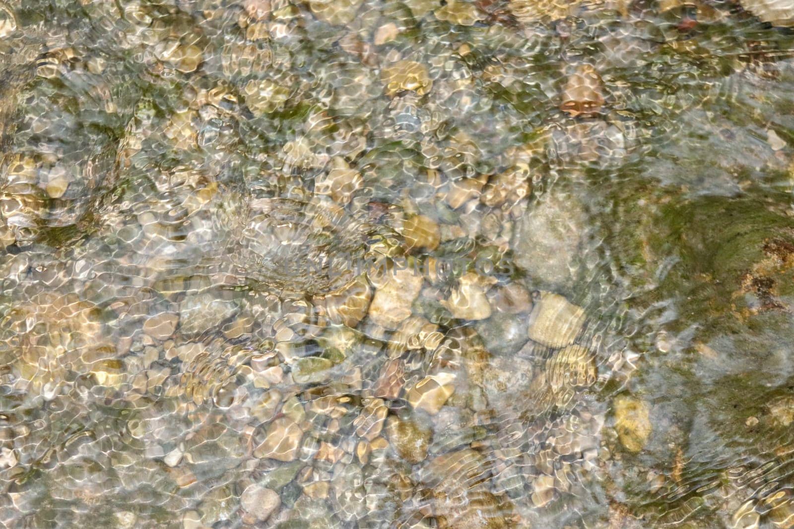 Waterfall stream close-up view from above clear flowing stream over ground gravel and stones. High quality photo