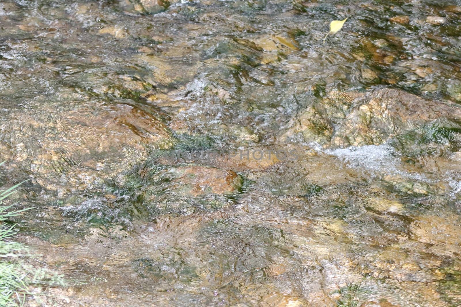 Waterfall stream close-up view from above clear flowing stream over ground gravel and stones. High quality photo