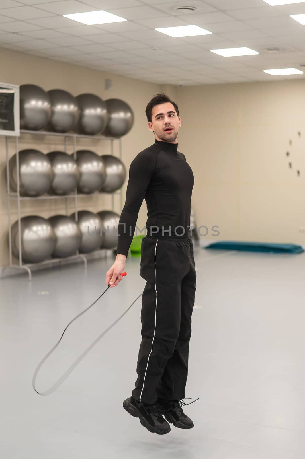 Caucasian man jumping rope in a fitness club. Vertical photo